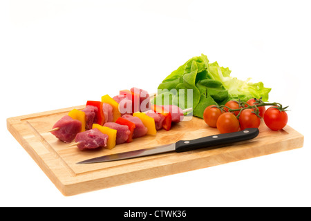 Brochettes de porc fraîchement préparés kebab sur une planche à découper en bois - studio photo avec un fond blanc Banque D'Images