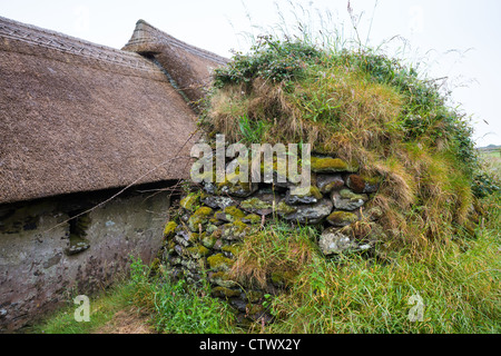 Mur en pierre sèche celtique beehive hut en encorbellement avec chalets et la Famine Museum, Fahan, péninsule de Dingle, comté de Kerry en Irlande. Banque D'Images