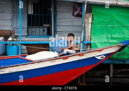 Petit enfant est assis à l'avant d'un bateau amarré à une maison flottante sur le lac Tonlé Sap, à Angkor Wat à Siem Reap au Cambodge. Banque D'Images