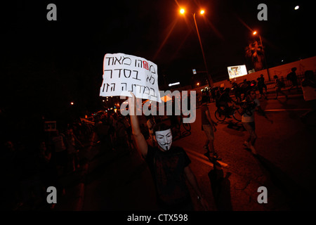 Un manifestant israélien portant un masque Guy Fawkes utilisé par le mouvement anonyme tient un panneau indiquant « une chose est totalement erronée dans ce pays » lors de la manifestation du coût de la vie à tel-Aviv Israël. La manifestation pour la justice sociale a également été appelée la manifestation de Tents, une série de manifestations en Israël à partir de juillet 2011 impliquant des centaines de milliers de manifestants issus de divers milieux socio-économiques opposés à la hausse continue du coût de la vie, en particulier du logement. Banque D'Images