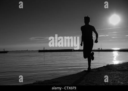 Sportsman ombragée chauffage jambes sur la plage en fin de soirée Banque D'Images
