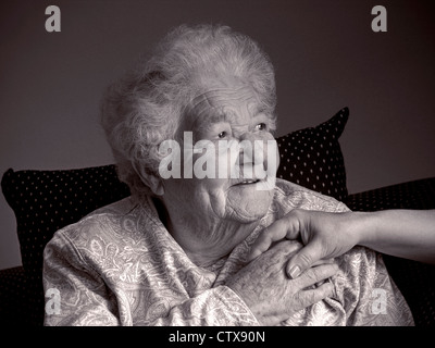 La haute atmosphère heureux retraité femme âgée détient main réconfortante du soignant dans sa salle de séjour ( B&W) Banque D'Images