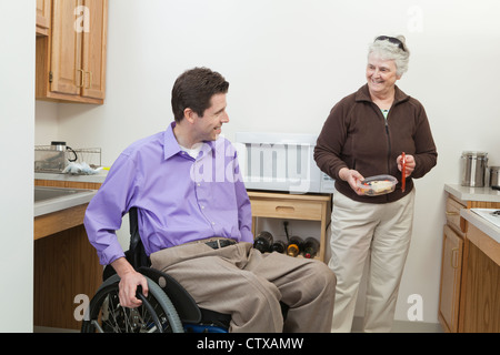 L'homme en fauteuil roulant avec de la moelle épinière obtenir de la nourriture de son domicile l'aide à la santé Banque D'Images