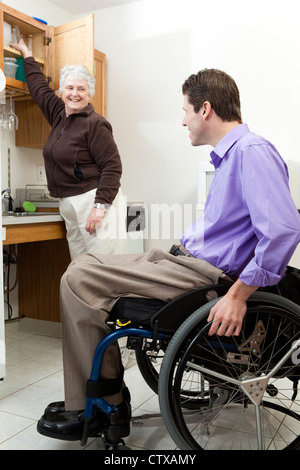 Accueil l'aide à la santé obtenir un verre pour un homme en fauteuil roulant avec de la moelle épinière Banque D'Images