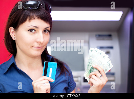 Belle femme en utilisant la carte de crédit, elle est le retrait d'argent d'un guichet automatique. Banque D'Images