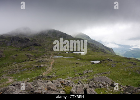 Trois Tarns, entre falaises et Bowfell ondulée, à l'égard couvertes de nuages Crinkle Crags, avec la région de Eskdale à droite Banque D'Images