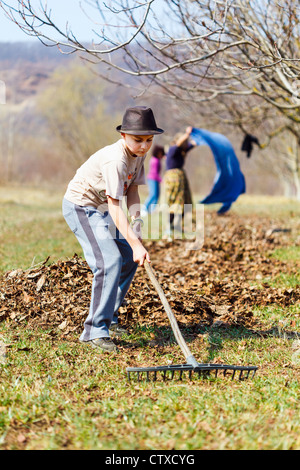 Grand-mère et petit-fils du grand ménage de printemps le verger de noyers avec râteaux Banque D'Images