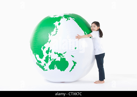 Une jeune fille serrant un globe vert Banque D'Images