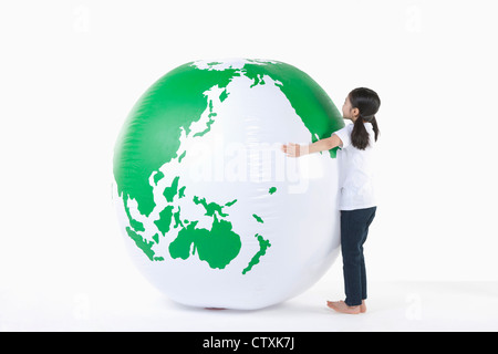 Une jeune fille serrant un globe vert Banque D'Images