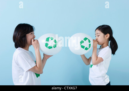 Une mère et sa fille soufflant ballons recyclage Banque D'Images