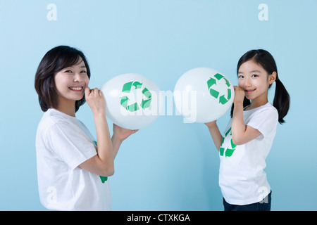 Une mère et sa fille soufflant ballons recyclage Banque D'Images