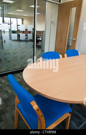 Salle de réunion vide table et chaises bleues à la recherche à travers une porte ouverte et moderne en verre dépoli à un open plan office Banque D'Images