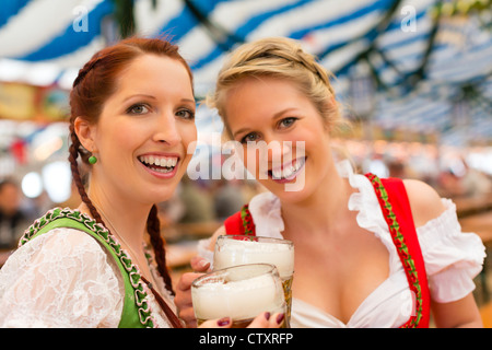 Les jeunes femmes en habits traditionnels bavarois dirndl - ou tracht - sur un festival ou dans une tente à bière Oktoberfest Banque D'Images