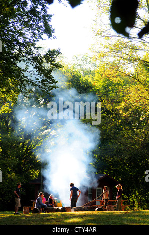 Les gens autour d'un feu de fumée dans une forêt d'été Banque D'Images