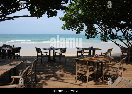 Tables et chaises en bois à côté de belle, plage exotique, Koh Sumet, Thaïlande. Banque D'Images
