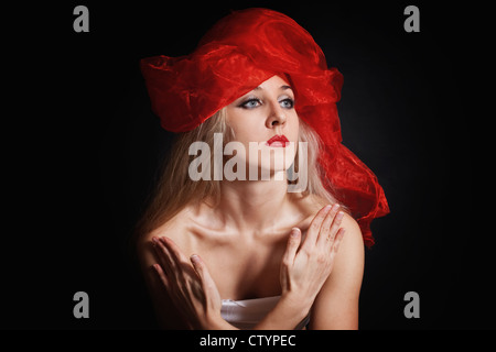 Portrait d'une jeune femme dans une coiffe rouge sur fond noir Banque D'Images