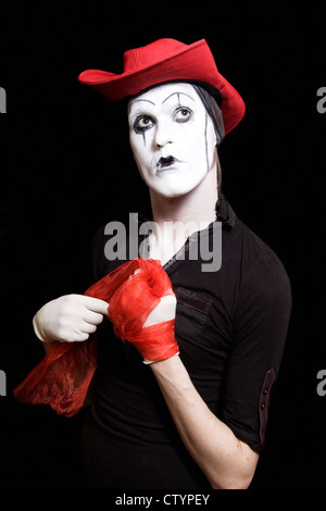 Mime dans un chapeau de cowboy rouge sur fond noir Banque D'Images