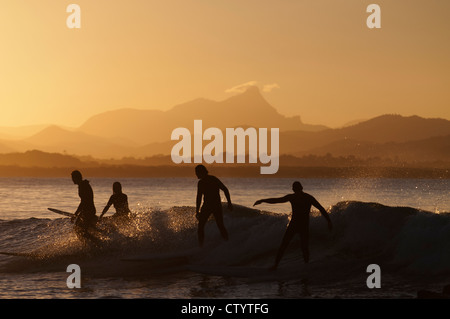 Surfers au coucher du soleil au col, à Byron Bay, avec Mt Warning en arrière-plan. Banque D'Images
