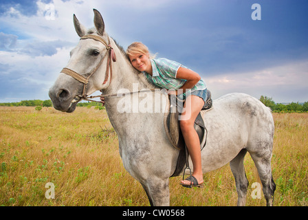 Les jeunes femmes adultes ride sur cheval gris sur un pré, est de l'Europe Banque D'Images