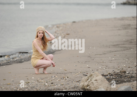 Femme accroupie sur plage de sable Banque D'Images