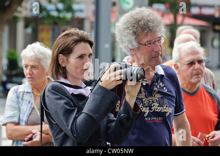 Femme adulte avec les cheveux bruns à prendre des photos avec l'appareil photo numérique Canon homme gris avec des cheveux bouclés et vieux regarder les gens Banque D'Images