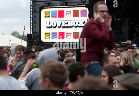 Un homme s'entretient sur mobile dans la foule devant la scène principale du festival lovebox à Victoria Park, Londres, juin 2012 Banque D'Images