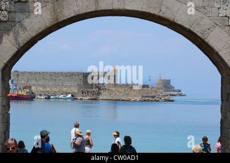 Une vue à travers une entrée voûtée de la vieille ville de Rhodes et à la recherche vers l'entrée du port fortifié et phare. Banque D'Images