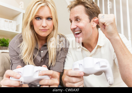 Une belle, jeune couple, homme et femme assis à la maison détendu jouant sur une console de jeu vidéo pour être compétitif, Banque D'Images