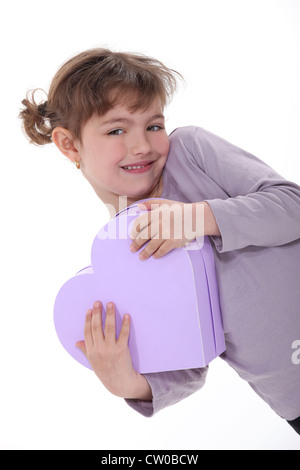 Adorable girl hugging a heart-shaped box Banque D'Images