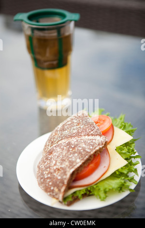 Close-up d'un jambon, fromage et tomate sandwich fait avec du pain de seigle. Verre de thé vert sur l'arrière-plan Banque D'Images