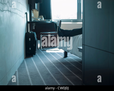 L'homme portant sur la chambre d'hôtel bed Banque D'Images