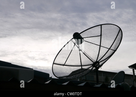 Antenne Satellite noire couverte par la rosée sur le toit lors de pleuvoir Banque D'Images