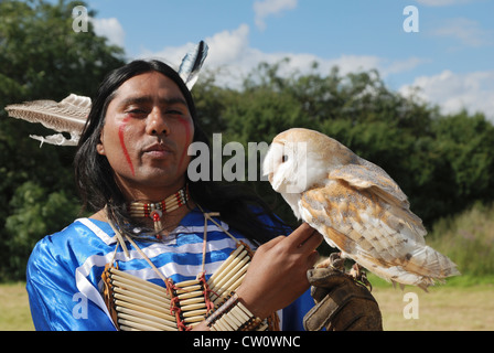 Un homme posant en Lakota (sioux) traditionnelle robe avec une chouette effraie. Banque D'Images