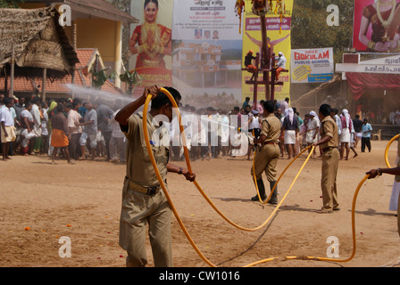 Les travailleurs de l'eau d'arrosage de la force du feu sur le sable chaud sur le Temple Pathways pour aider à Garudan thookkam à Kerala Inde rituel Banque D'Images