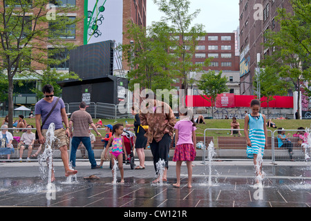 Les gens en phase de refroidissement les pieds dans la pulvérisation d'eau de la Place des festivals au centre-ville de Montréal, province de Québec, Canada. Banque D'Images