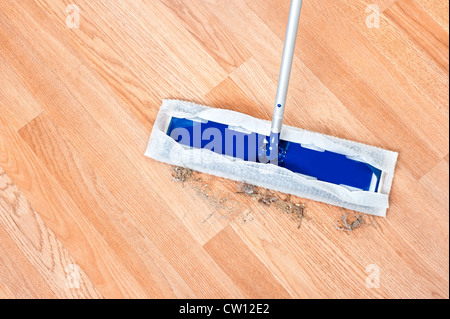 Image d'un étage moderne dusting mop utilisée pour nettoyer les cheveux et la saleté sur un plancher en bois laminent. Banque D'Images