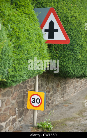 Carrefour et 30 milles à l'heure signe de la circulation en if hedge au village de Brampton Bryan, Herefordshire, Angleterre, RU Banque D'Images