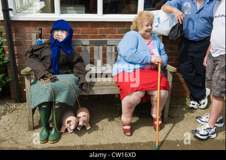 Effigie de la Reine s'assit sur un banc de travail avec dame âgée au cours de la Journée de l'épouvantail dans village de Brampton Bryan Herefordshire Angleterre UK Banque D'Images