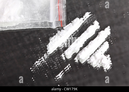 Poudre de cocaïne en lignes et de paquets sur le miroir, gros plan Banque D'Images
