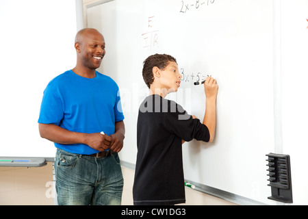 Professeur de mathématiques de l'Amérique africaine aider un étudiant d'effectuer une pré-algèbre sur le conseil. Banque D'Images