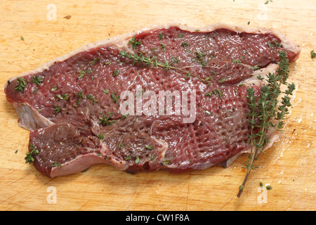 Un tenderised pavé de rumsteak, enduits d'huile d'olive et saupoudré de thym et de poivre. Banque D'Images