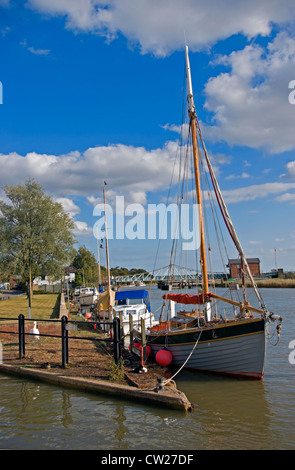 Bateaux amarrés le long de la rivière Yare à Reedham de Norfolk, avec le pont tournant de chemin de fer au-delà. Banque D'Images