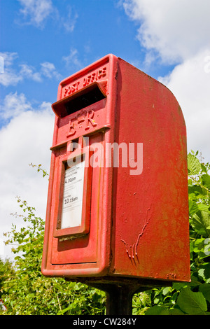 Une vieille petite rouge post box contre un blue cloudy sky Banque D'Images