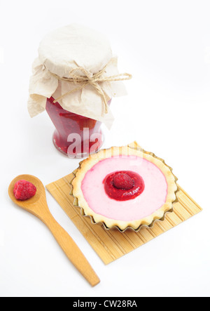 Pot de confiture de framboises, tarte à la crème et cuillère en bois avec des fruits Banque D'Images