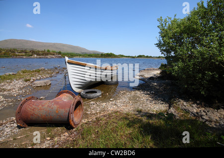 Vieux bateau avec une étrange, d'ancrage dans un lac tranquille en Irlande Banque D'Images