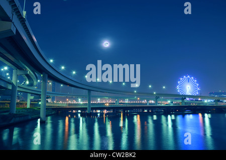 Pendu à l'autoroute la route sur les eaux de la baie de Tokyo de nuit avec lune et ferris roues arrière sur l'éclairage Banque D'Images