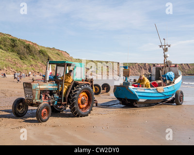 Filey Sands Yorkshire UK.Tracteur tirant coble pêche à terre Banque D'Images