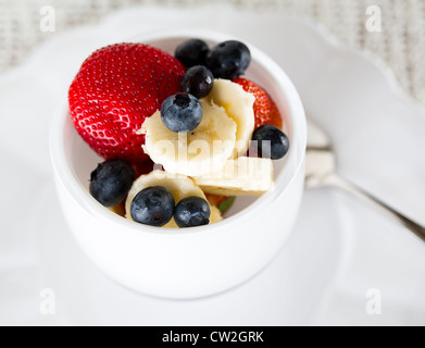 Petit-déjeuner de bleuets, fraises avec banane dans bol en verre Banque D'Images