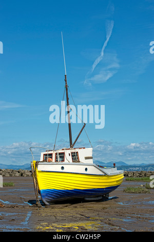 Bateau de pêche en bois jaune garé par la marée dans la baie de Morecambe, Lancashire Banque D'Images