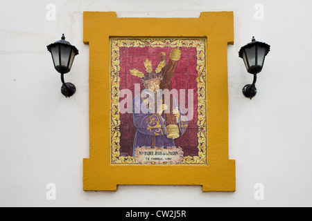 Chris Jésus portant la croix, un carrelage en céramique Azulejo sur un mur d'une maison dans le vieux quartier juif, Cordoba, Espagne. Banque D'Images